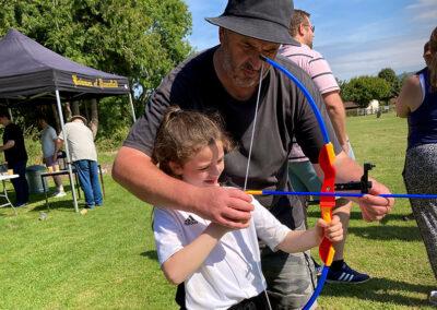 Summer Fun Day and BBQ 2023 Courtenay showing Isla how to shoot a barebow